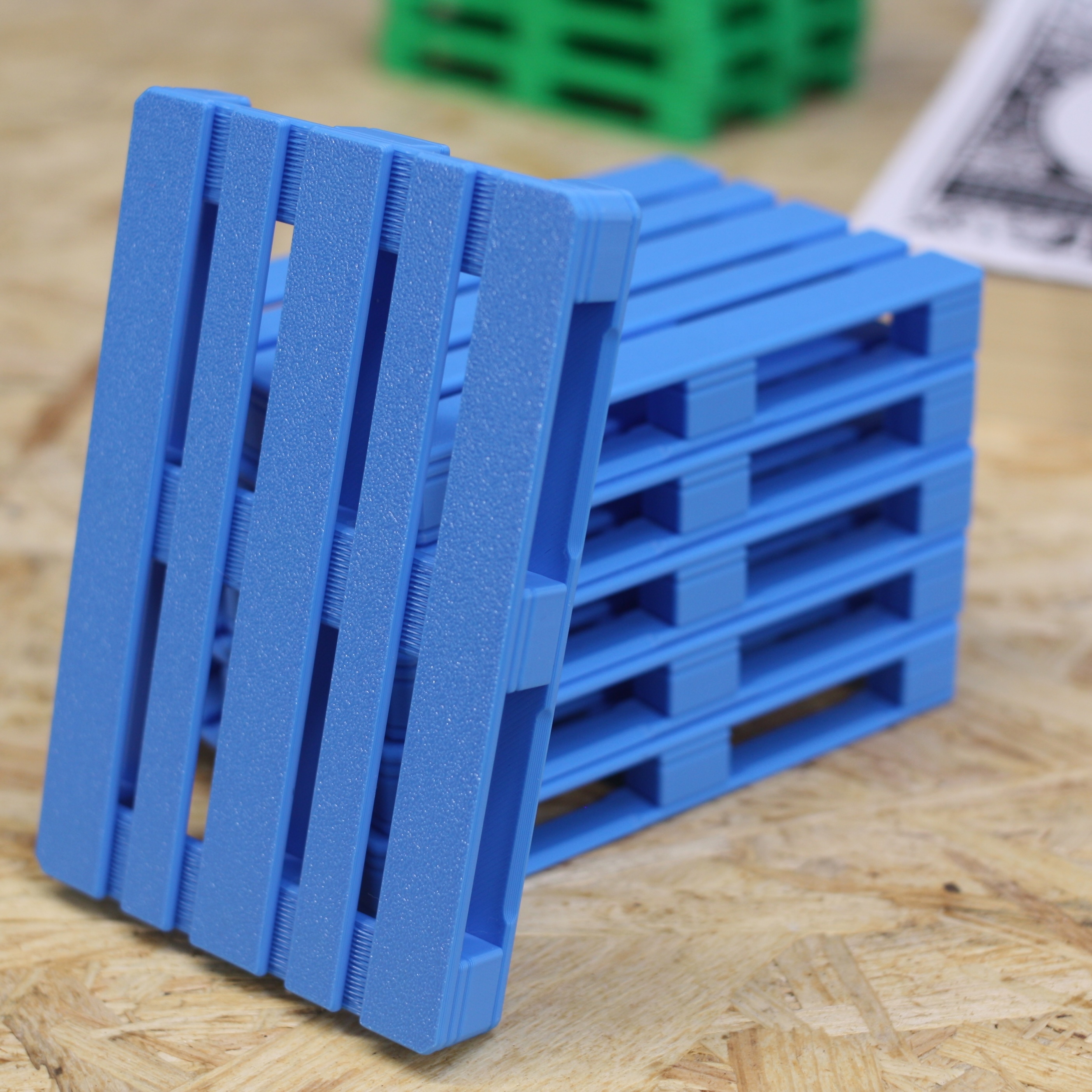 Blue mini pallets — one leaning against a stack, angled view